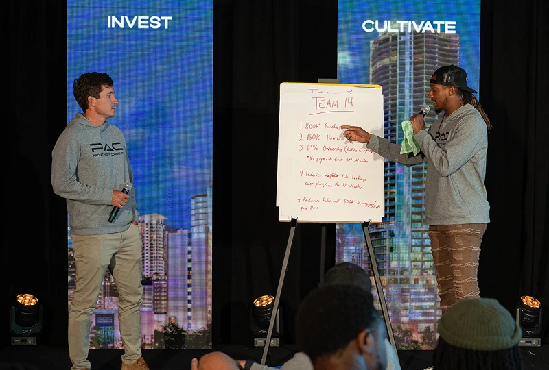 two men with mics host an event with whiteboard